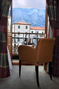 a chair sitting in front of a window with a view at Hotel Vardar in Kotor