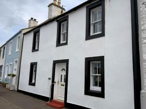 - un bâtiment blanc avec des fenêtres noires dans une rue dans l'établissement Pass the Keys Gorgeous 3 BR Cottage with Outstanding Sea Views, à Isle of Whithorn