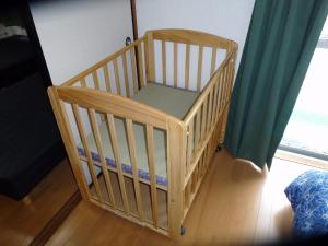 ein Kinderbett in einem Zimmer neben einem Fenster in der Unterkunft MIYUKIHOUSE1番館201 wi-fi babybed wii in Kasugabaru