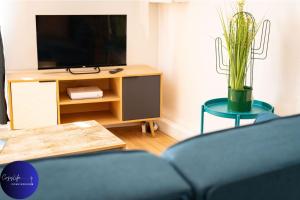 a living room with a tv and a blue couch at La Chrysalide by CozyLife - Centre Ville in Niort +9 photos