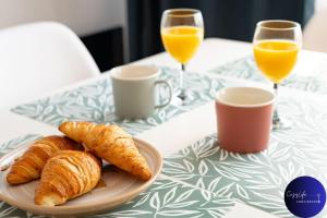 a plate of croissants on a table with glasses of orange juice at La Chrysalide by CozyLife - Centre Ville in Niort