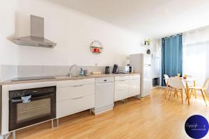 a kitchen with white appliances and a table with chairs at La Chrysalide by CozyLife - Centre Ville in Niort