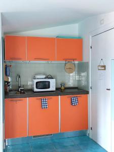a kitchen with orange cabinets and a microwave at Casa Blu with Sea View - Borgo Stays in Sperlonga +11 photos