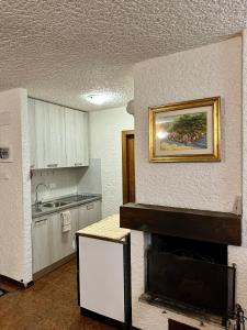 a kitchen with a fireplace and a painting on the wall at Dimaro-Folgarida Apartment in Monclassico