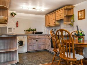 a kitchen with wooden cabinets and a table and chairs at The Shippon in Appletreewick