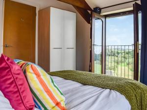 een slaapkamer met een bed en een groot raam bij Sandymouth Cottage in Marhamchurch