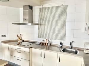 a white kitchen with a sink and a counter top at Gijón Playa San Lorenzo Parking incluido in Gijón