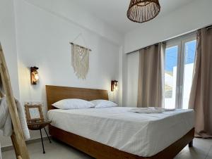a bedroom with a bed with white sheets and a window at Aenya Kythnos Villas in Kithnos