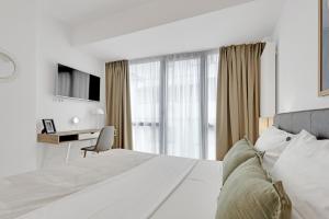 a bedroom with a bed and a desk and a television at UpHome Suites in Bucharest