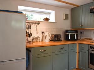 a kitchen with green cabinets and a white refrigerator at Kiln Cottage in Bolton le Sands
