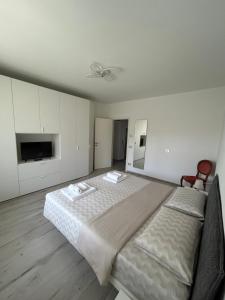 a white bedroom with a large bed and a tv at Appartamento Rajmonda in Luino