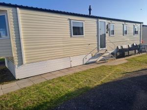 a mobile home with two chairs in front of it at Trecco Bay Cwtch Caravan in Newton