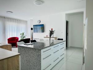 a white kitchen with a counter and a red chair at Villa Moderne MARIA-VIDA Piscine Medugorje 2km Mostar 22km in Međugorje