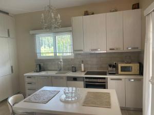 a kitchen with white cabinets and a table and a microwave at Villa Fay in Preveza