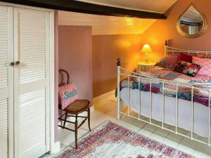 une chambre avec un lit, une chaise et un miroir dans l'établissement The Grooms Cottage-Uk45659, à Bishops Castle