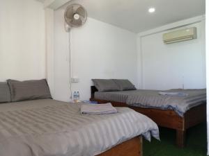 a bedroom with two beds and a fan on the wall at SokSan Seaview Cottage in Koh Rong Island