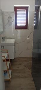 une salle de bain avec un lavabo et des toilettes et une fenêtre dans l'établissement Apartmani Anna, à Rogoznica 29 autres photos