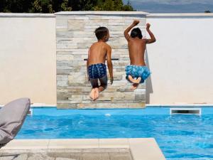 two young boys jumping into a swimming pool at Villa Moderne MARIA-VIDA Piscine Medugorje 2km Mostar 22km in Međugorje