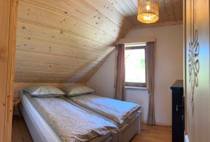 a bed in a room with a wooden ceiling at Cicha Ostoja in Czarny Dunajec