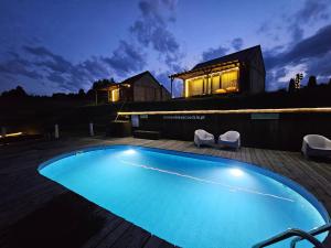 a swimming pool at night with a house in the background at Chata w Bieszczadzie SPA apartamenty i domki z podgrzewanym basenem in Polańczyk