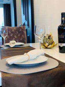a table with a plate with a bottle of wine and glasses at Local-Lux Apartman 3 szoba, privát parkoló in Kecskemét