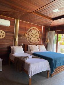 two beds in a room with wooden walls at Villa Caravelas Praia de Moitas in Amontada