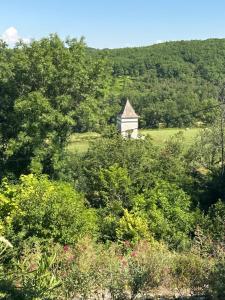 an old house in the middle of a field with trees at Le clos des Oiseaux in Itzac