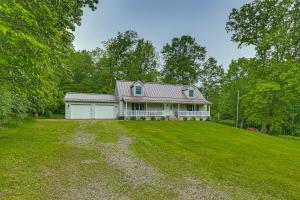 a white house with a garage on a grass field at 2 Mi to Woodbury Wildlife Area Cozy Farmhouse! in Warsaw