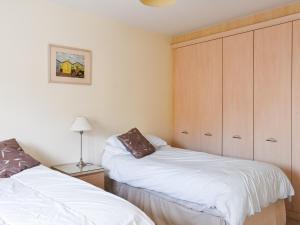 a bedroom with two white beds and a cabinet at Lime Court - Cottages in Leatherhead +4 photos