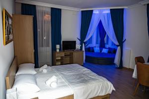 a bedroom with a bed and a television and blue curtains at Hotel Port Altus in Batumi