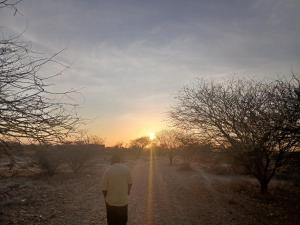 a man walking down a dirt road at sunset at Tarangwe Homestay & Hostels in Iringa