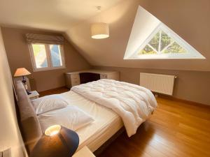 Un dormitorio con una gran cama blanca con ventana. en Villa des Pins Hardelot, en Neufchâtel-Hardelot