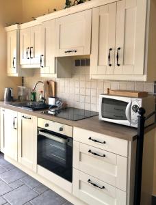 una cucina con mobili bianchi e un forno a microonde di Town center duplex with lift a Clonakilty