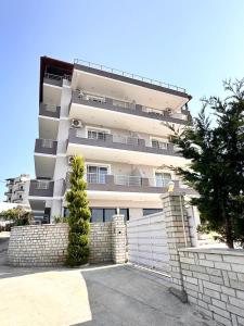 een hoog wit gebouw met een hek ervoor bij Golden Berden Boutique Apart-Hotel in Çukë