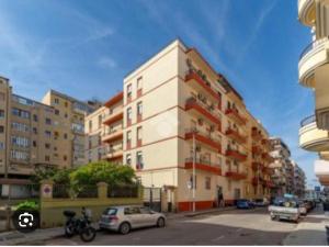 a tall white building with cars parked in front of it at Cagliari Essence - Boutique Stay in the Heart of Cagliari in Cagliari