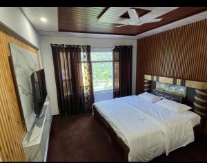 a bedroom with a large bed and a television at ROYALE PEAKS Sonamarg rd in Sonāmarg