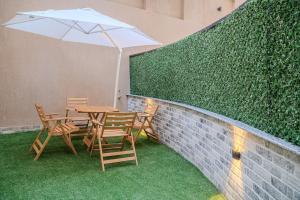 a table and chairs with an umbrella next to a wall at Modern 2BR - Private Garden Nook in Cairo