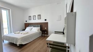 a white bedroom with a bed and a table at La fontanella apartment in Monopoli