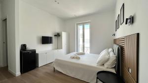 a white bedroom with a bed and a tv at La fontanella apartment in Monopoli