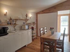 a kitchen with white cabinets and a table and a table and a dining room at chalet de Campagne avec option - petit déj in Wicquinghem