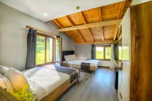 two beds in a room with wooden ceilings and windows at Ayder Palazzo Hotel in Ayder Yaylasi