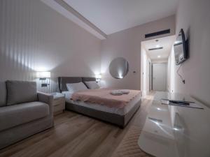 a white bedroom with a bed and a couch at CASA AL MARE RESIDENCE in Bečići