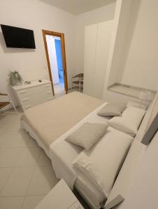 a white bedroom with two beds and a tv at 73059 Versilia in Fontanelle