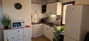 a kitchen with white cabinets and a clock on the wall at Appartement climatisé avec piscine, magnifique vue mer, lac et le Pic le Canigõ ! in Le Barcarès