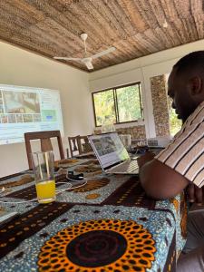 a man sitting at a table with a laptop computer at JozaniBiospherevillage in Jozani