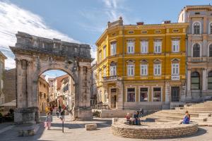 a building with an arch and people walking in front of it at Apartman Cukar Pula in Pula
