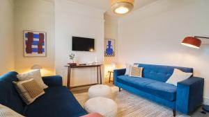 a living room with two blue couches and a tv at Crookes Gem with Garden & Alpacas Nearby in Walkley