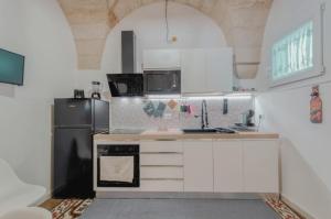 a kitchen with white cabinets and a black refrigerator at Il Melograno in Cavallino di Lecce