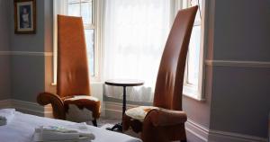 two chairs in a room with a bed and a window at The Loriston in Eastbourne