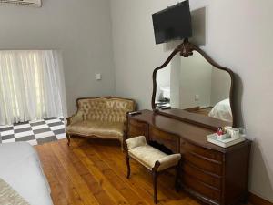 a bedroom with a dresser with a mirror and a chair at Boutique at milner guesthouse in Bloemfontein